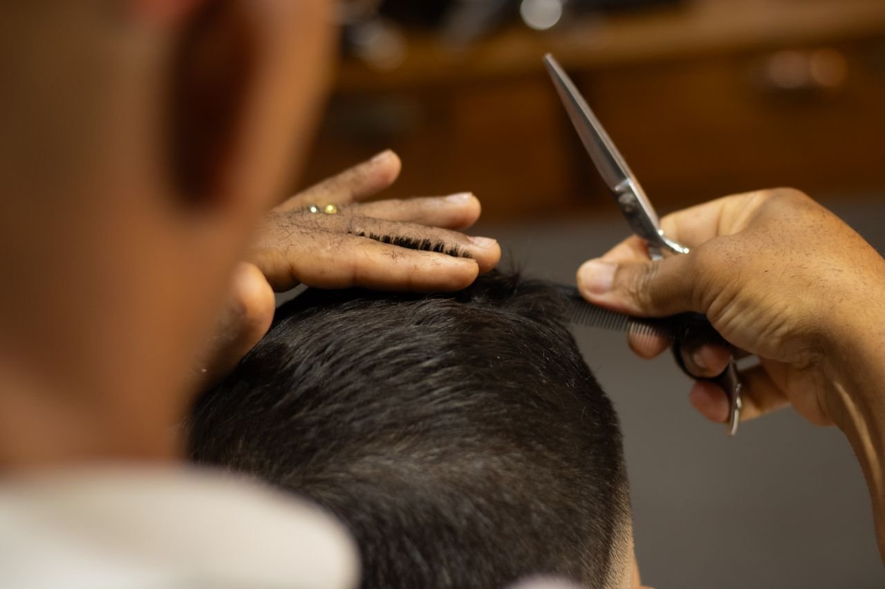 Close-up of a barber expertly cutting a mans hair in a salon. Professional grooming.